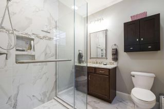 Elegant bathroom interior featuring a glass shower with marble tiles, dark wood cabinets, and modern fixtures.