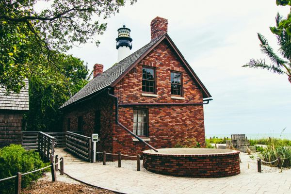 A charming brick house near the Cape Florida Lighthouse, Key Biscayne, surrounded by lush greenery.