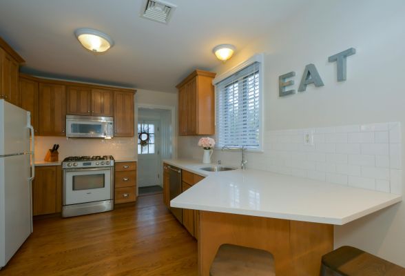 A clean, modern kitchen interior featuring wooden cabinets and a white countertop.