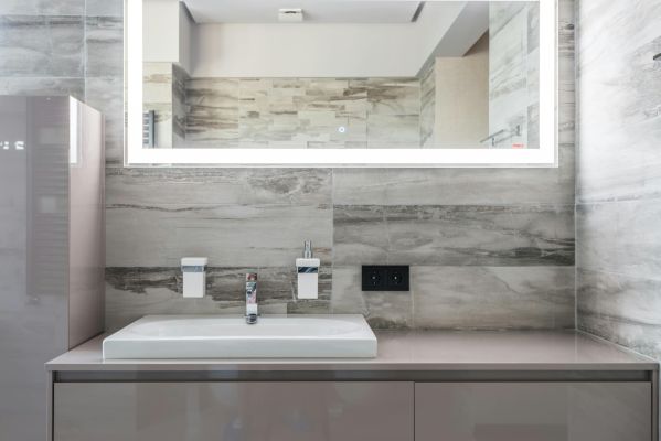 Sleek and clean bathroom design featuring an illuminated mirror and minimalist decor.