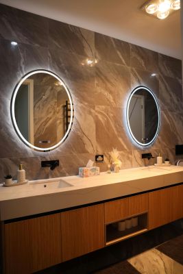 Elegant bathroom interior featuring a double vanity with circular backlit mirrors, sleek design.